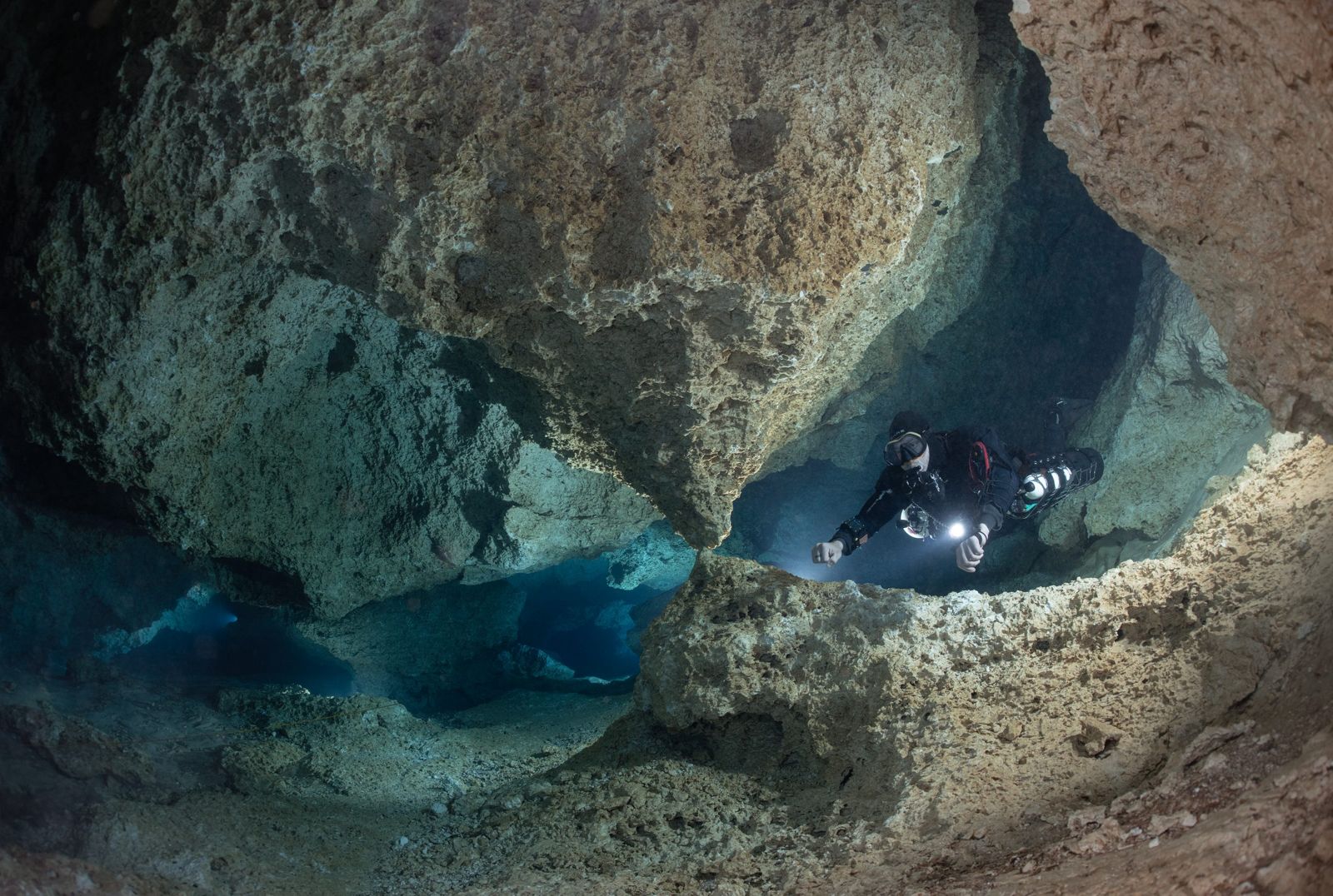Sidemount diver lighting up a limestone cave passage in North Florida