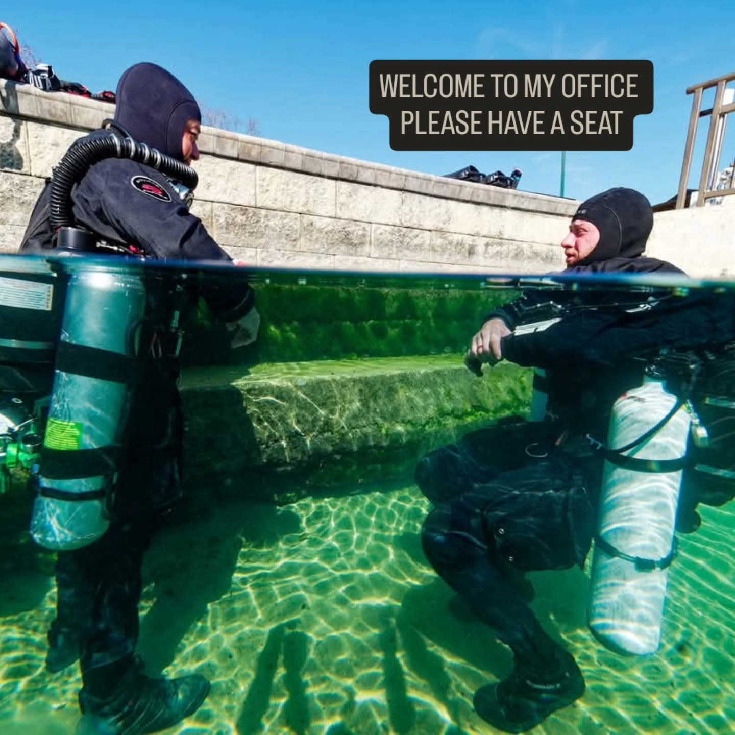 Two divers in drysuits and sidemount sitting in a clear Florida spring, captioned Welcome to my office, please have a seat